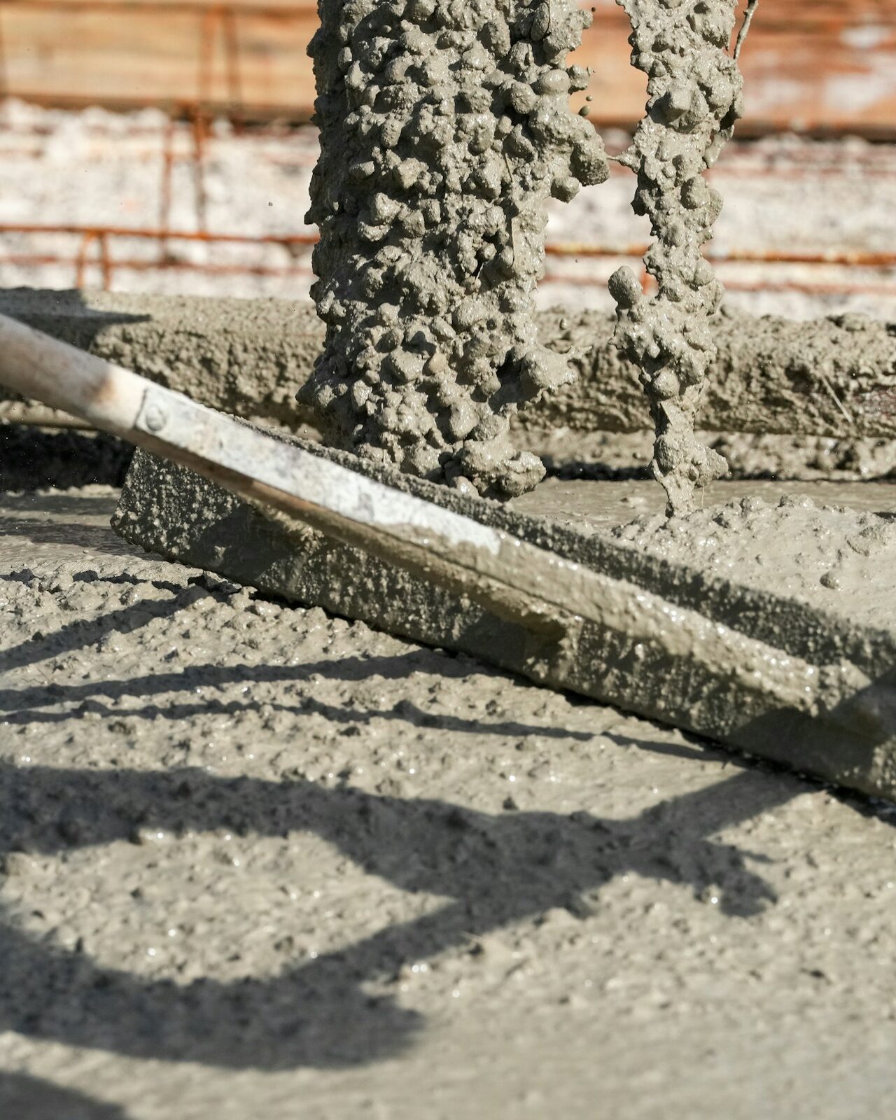 Estrich wird mit einer Kelle auf einer Bewehrung glatt gezogen