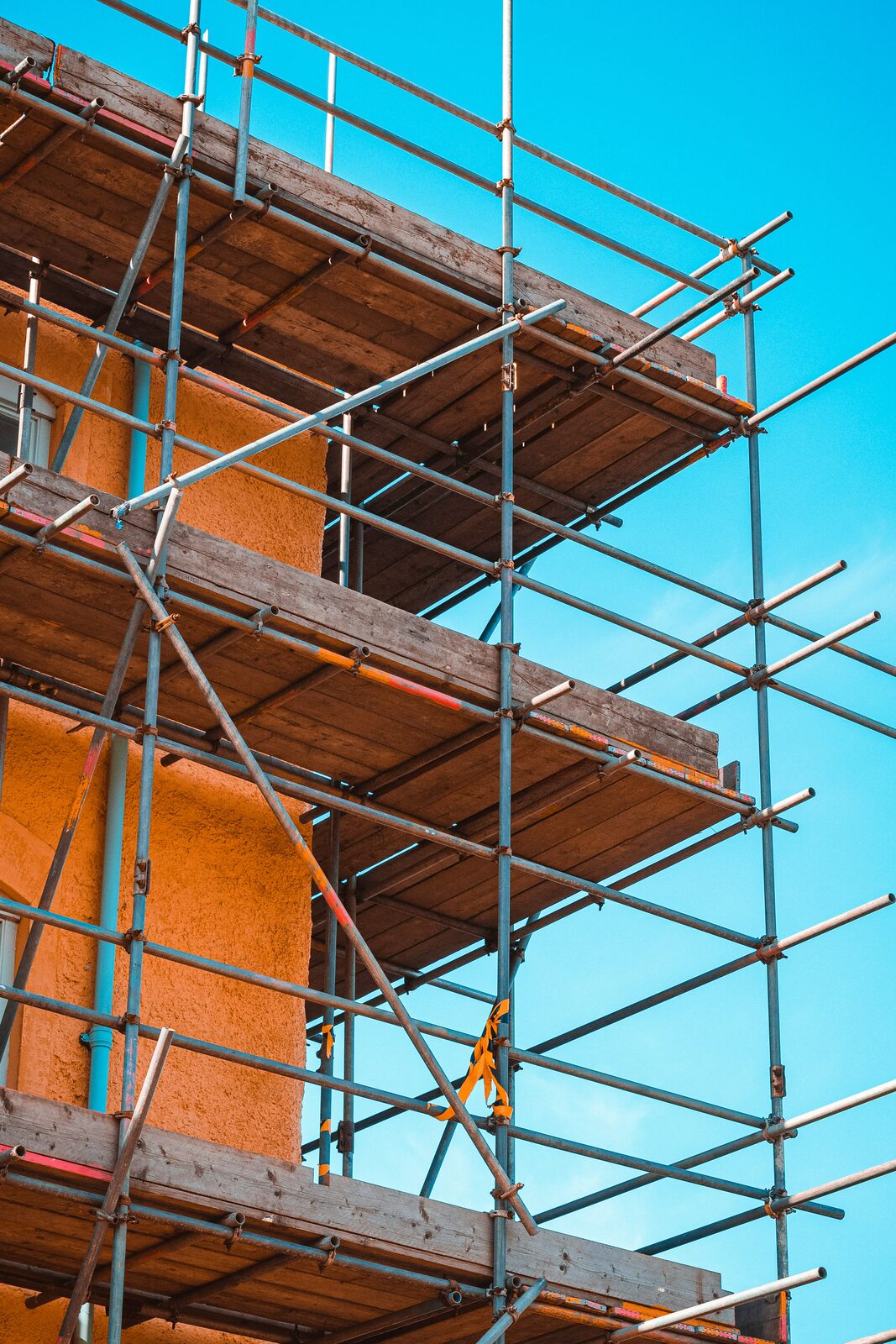 Eingerüstete Fassade eines Wohngebäudes mit Holzbohlen und Stahlrohren